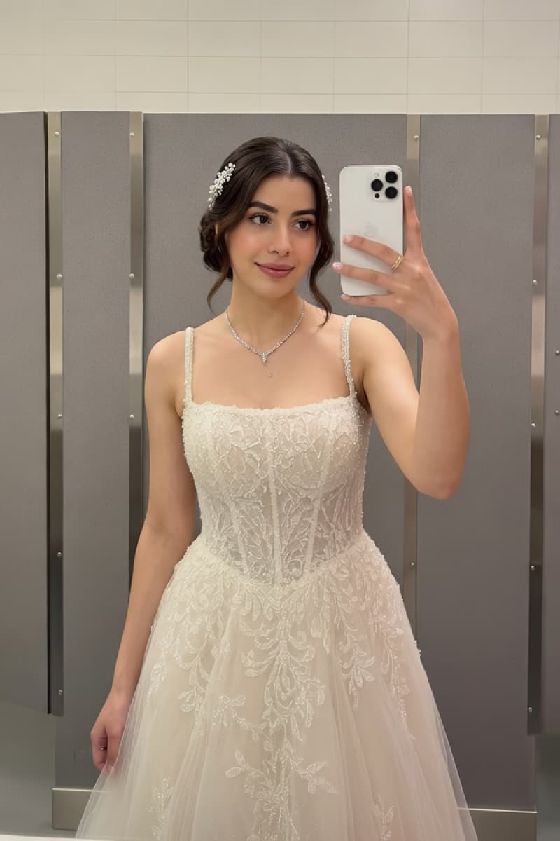 Young woman taking a mirror selfie while wearing an elegant ivory wedding dress
