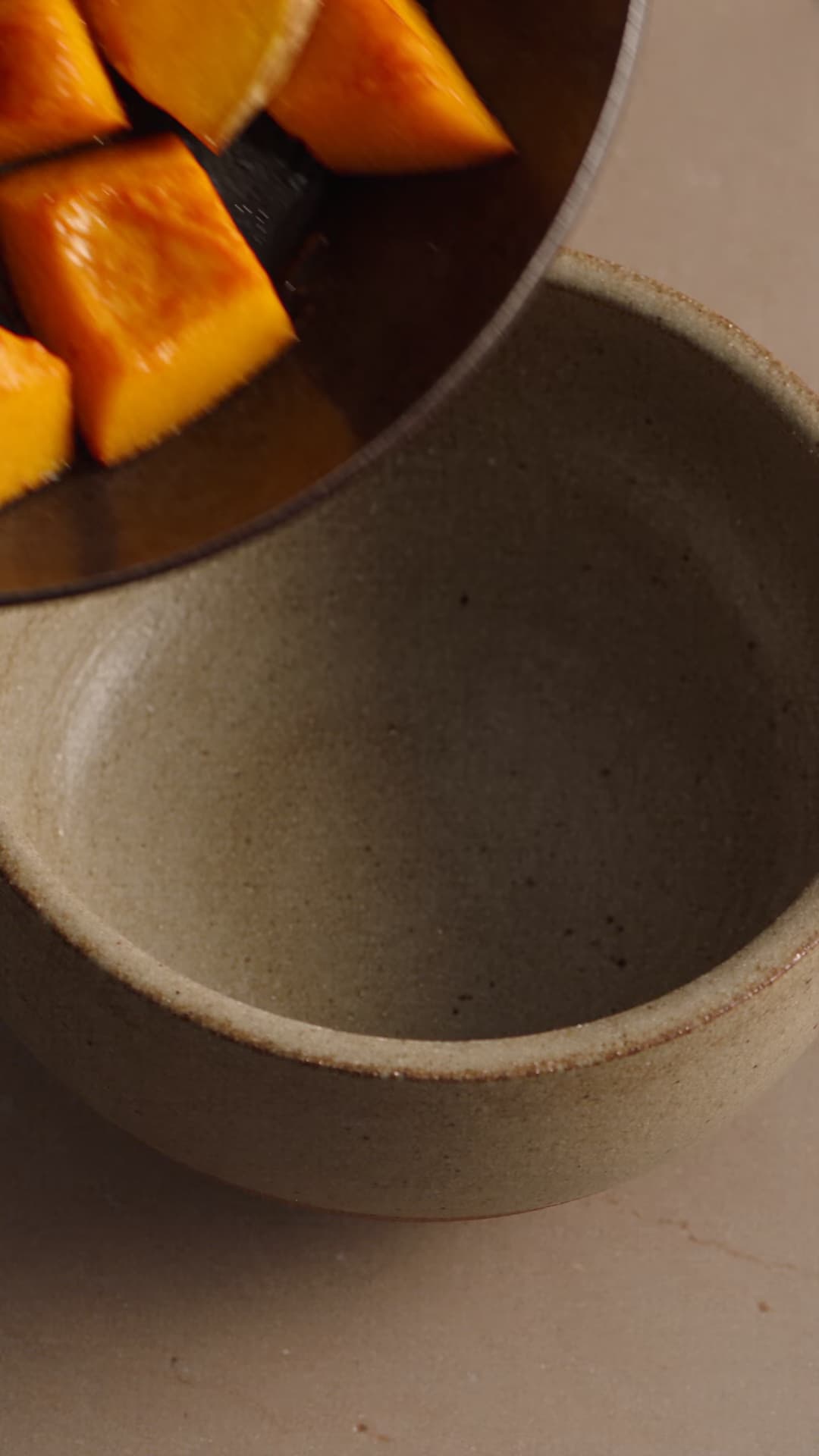 Roasted squash and herbs moving from tray to serving bowl.