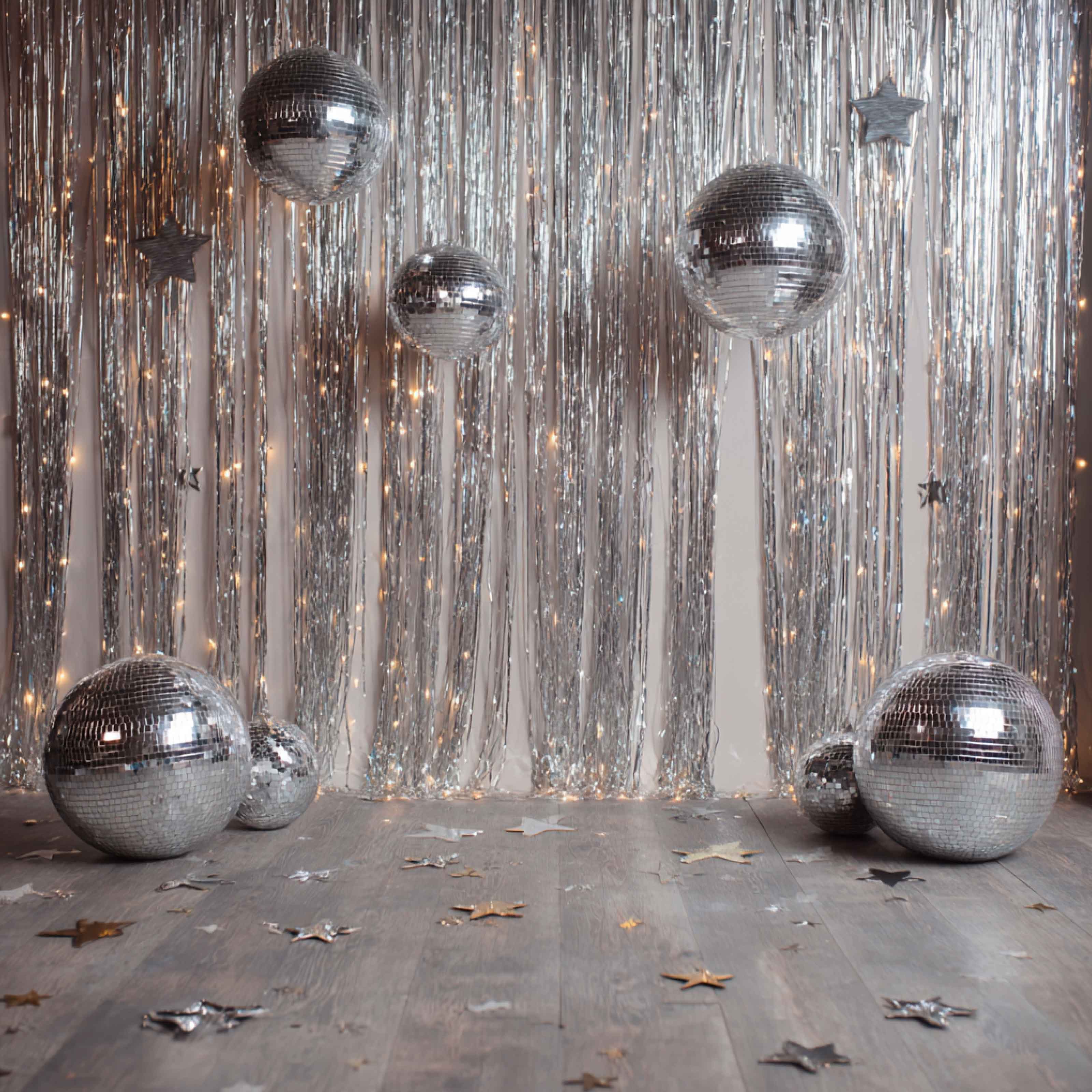 Silver balloons and a tinsel curtain set up for a birthday party