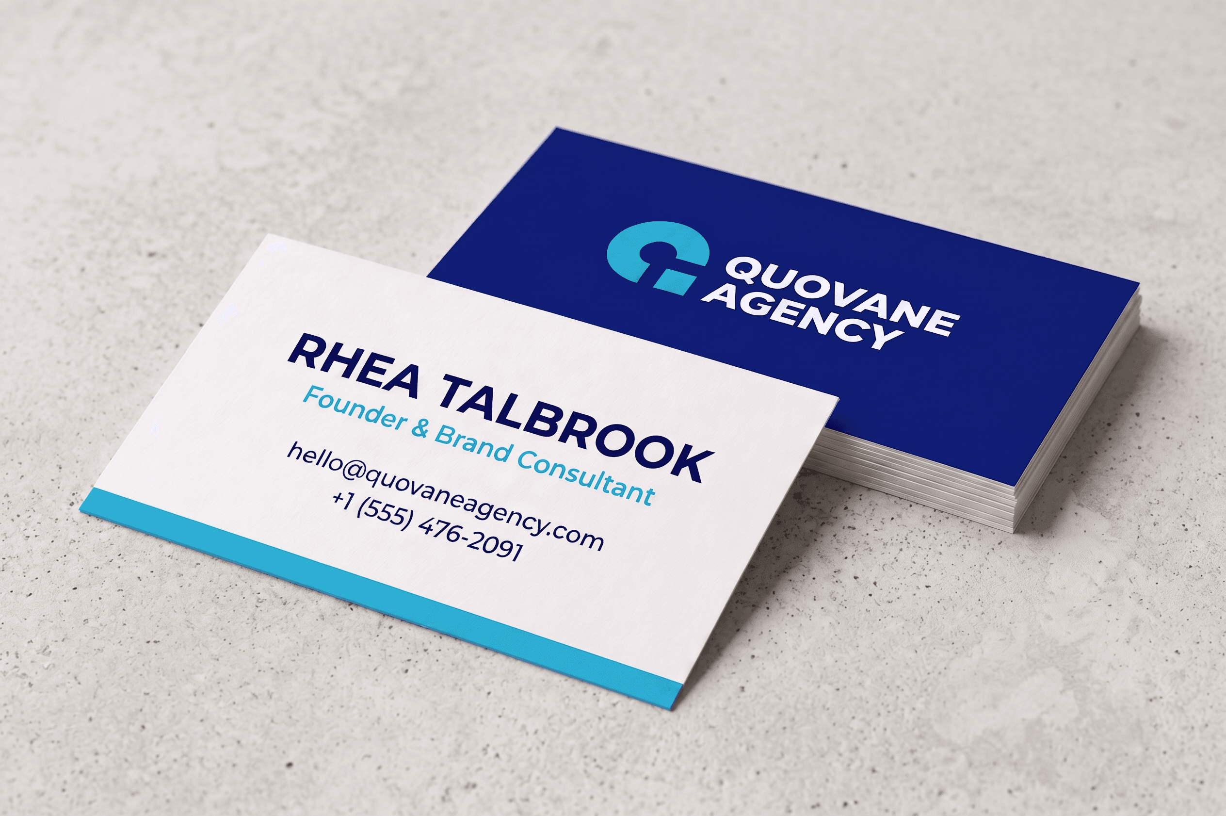 Printed business cards for Quovane Agency, front and back, on a concrete surface