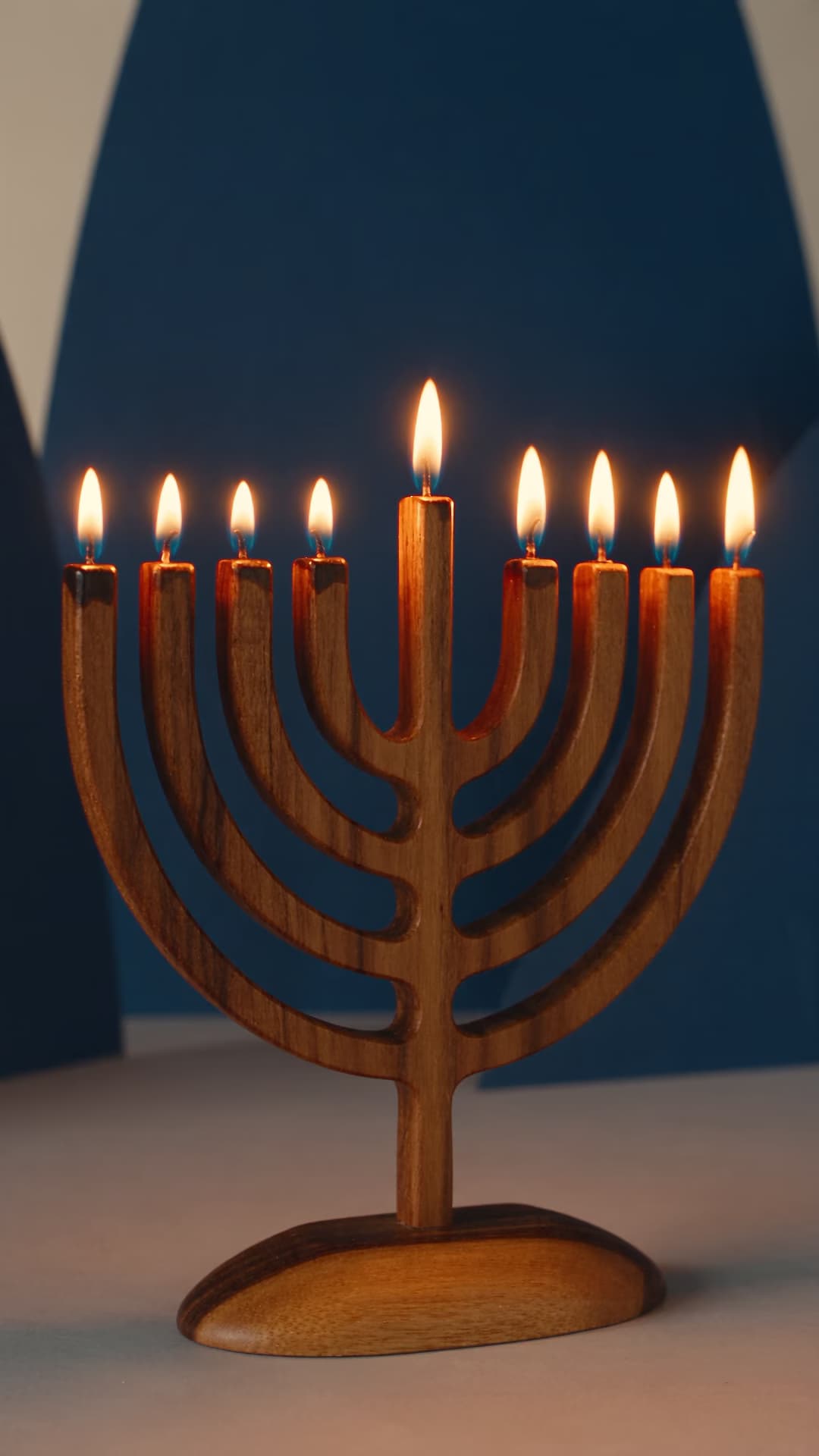 Nine-branched hanukkiah with raised shamash in warm candlelight.