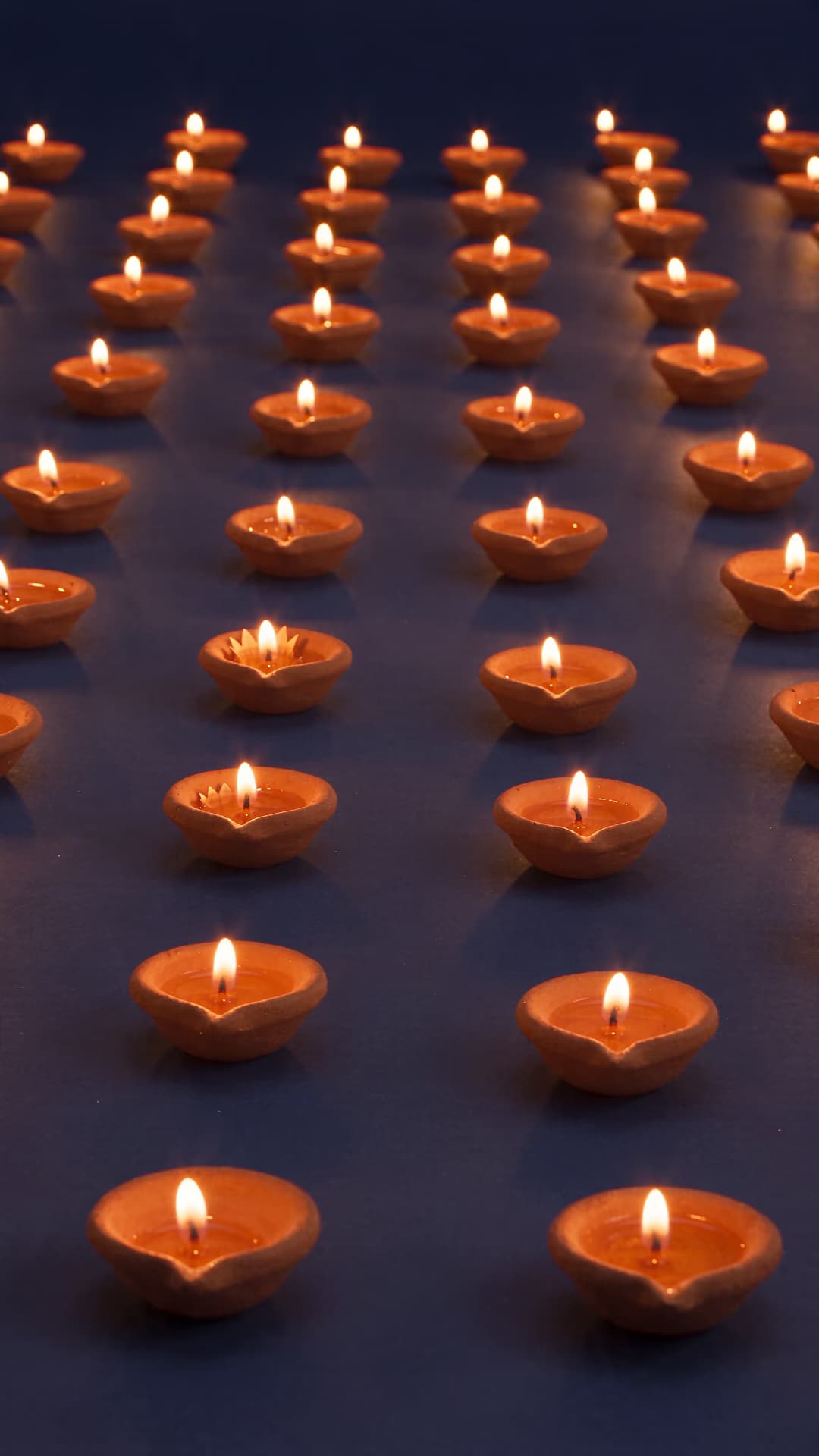 Clay diyas glowing across an indigo paper scene.