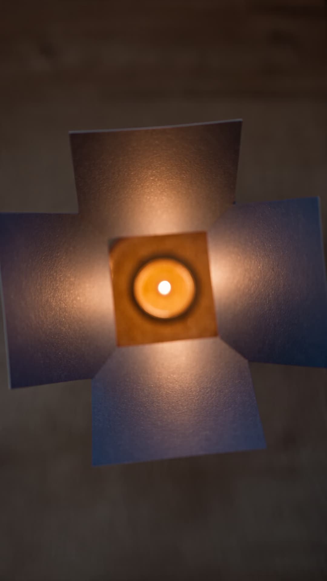 Indigo and cream cards rotating around a diya reflection.