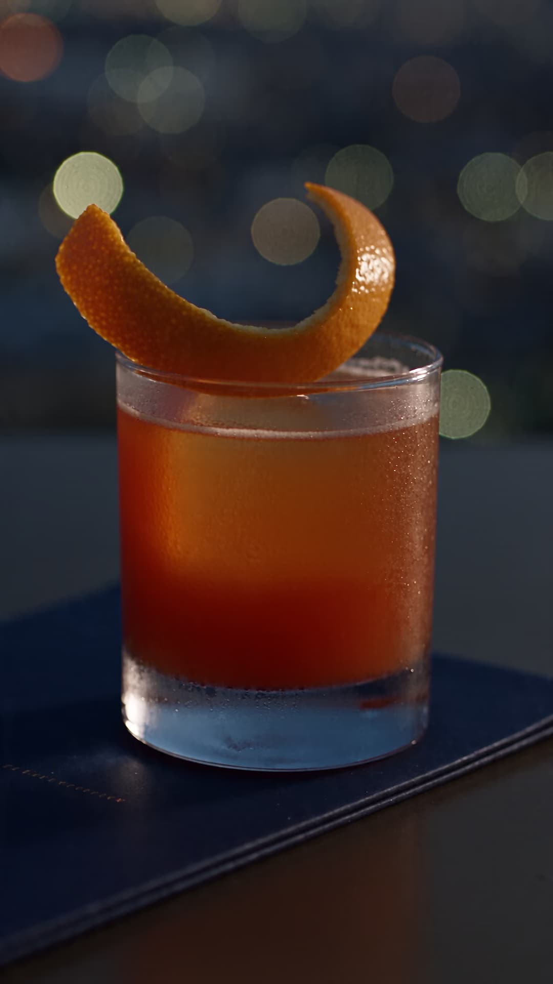 Original mocktail reflecting city lights at a rooftop venue.